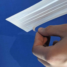 Load image into Gallery viewer, Forefinger and thumb peeling back the wax paper backing exposing the adhesive on the edge of a white SAM face covering.